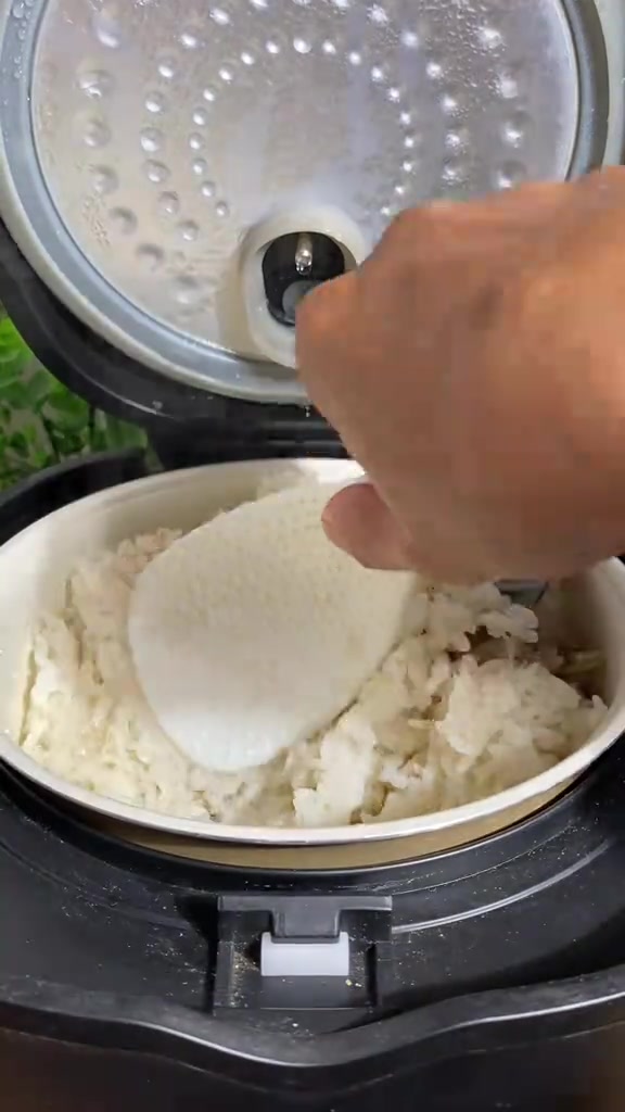Nasi lemak yang sedang diaduk rata di dalam panci rice cooker pada tahap warm