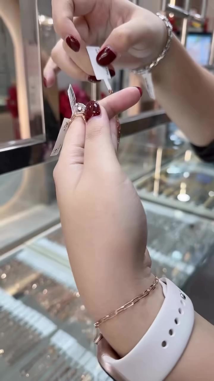 Tangan memegang rantai paperclip bertag harga sementara di pergelangan terlihat gelang paperclip warna rose gold