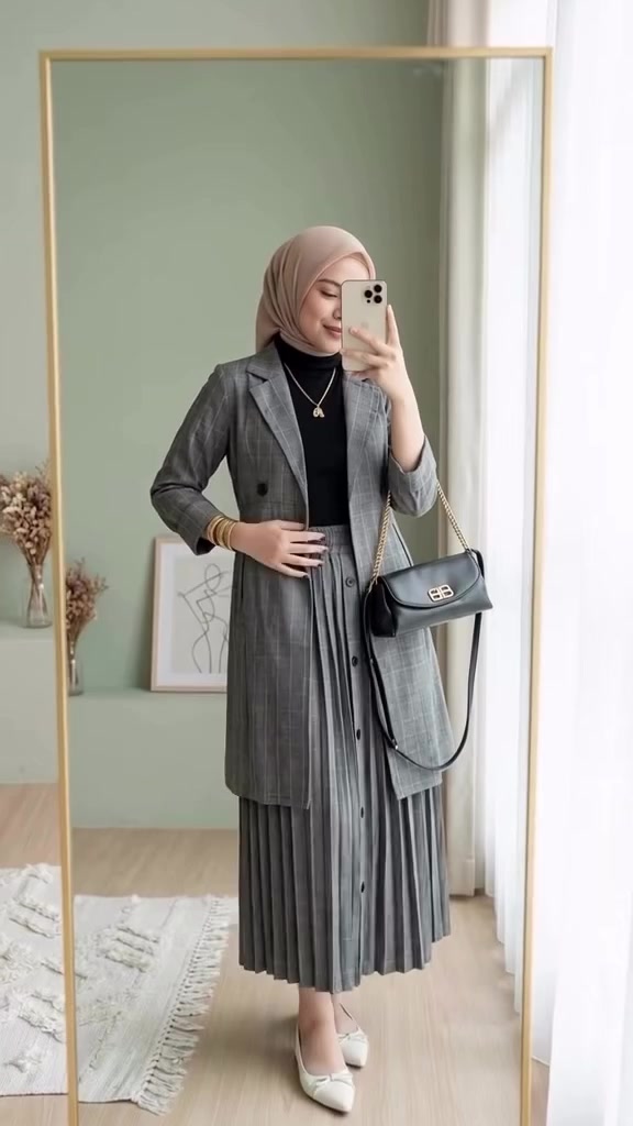 Selfie cermin perempuan berhijab memakai long blazer abu-abu motif kotak di atas inner hitam dan rok plisket abu-abu, membawa tas selempang hitam