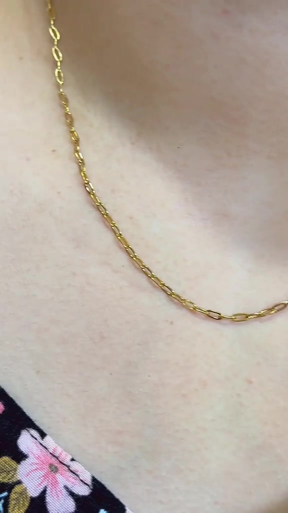 Close-up mata rantai kalung model paperclip warna gold yang terjuntai di atas kulit