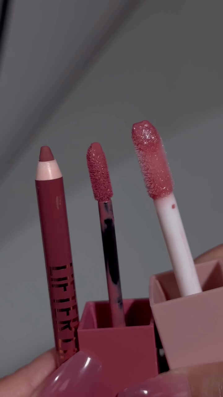 Ujung pensil lip liner dan dua aplikator lip product diangkat berdampingan di depan kamera