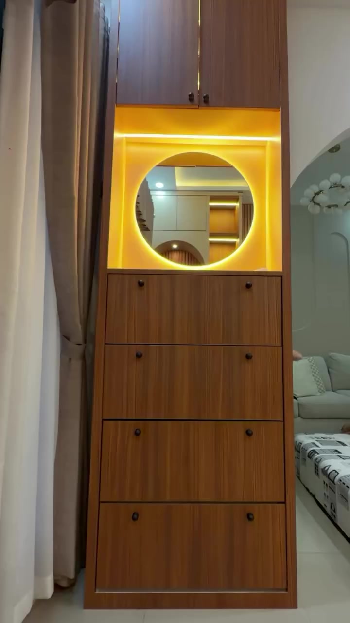 Kolom kabinet kayu bagian dari backdrop TV custom dengan cermin bulat berlampu LED kuning dan deretan laci