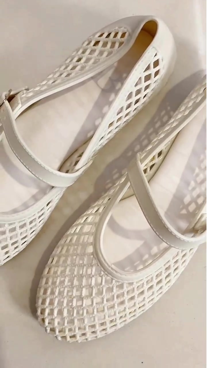 Sepasang sepatu mary jane putih bahan jelly berlubang dengan strap tunggal di permukaan terang