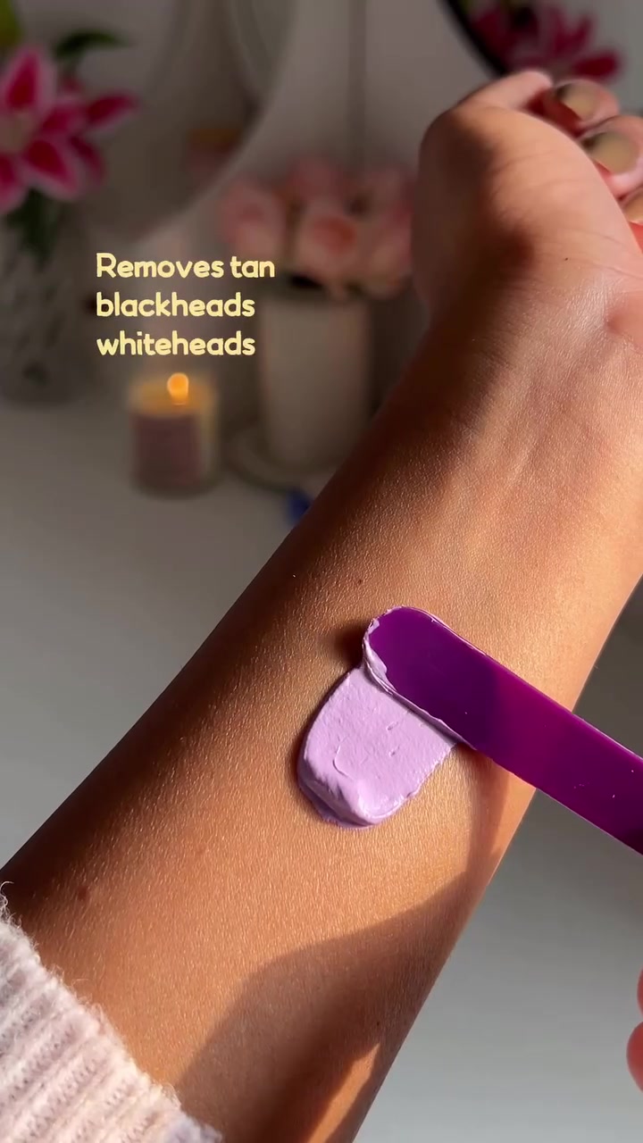 Swatch clay mask warna lilac dioles rata di lengan bawah menggunakan spatula