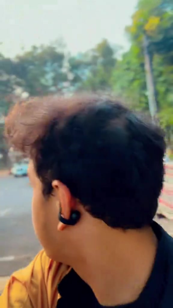 Pelari tampak dari belakang di jalan kota dengan earbuds open-ear tersangkut di telinga