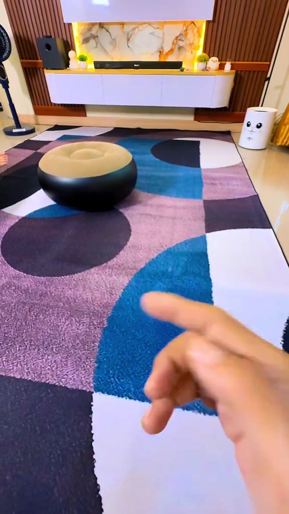 Ruang keluarga dengan karpet permadani motif geometris biru dan ungu di depan kabinet TV melayang