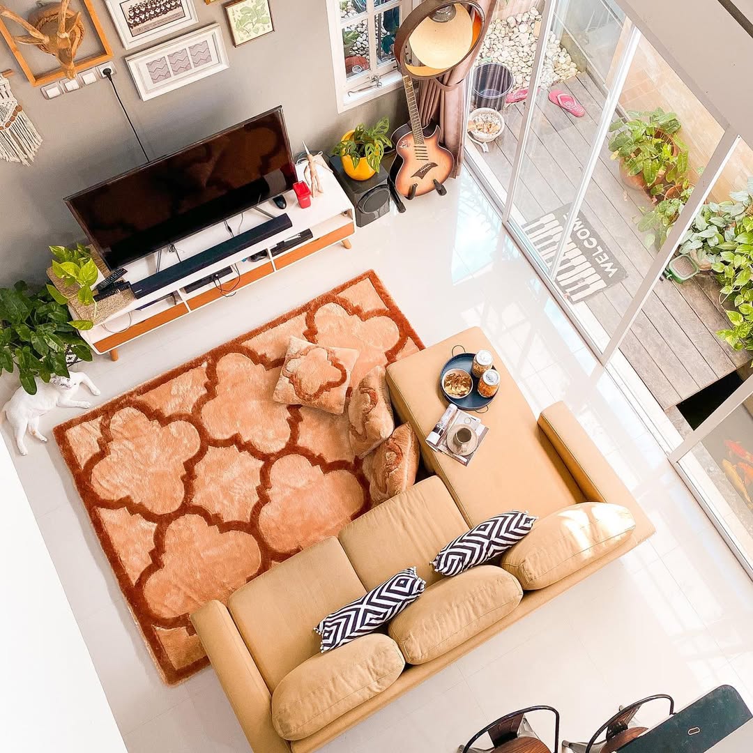 Tampak atas ruang tamu dengan karpet rasfur motif coklat yang menahan sofa dan bantal lantai