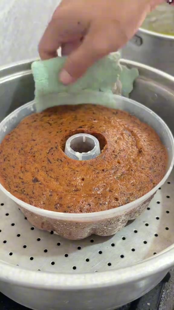 Bolu pisang dalam loyang bundt di dalam kukusan dengan permukaan mengilap