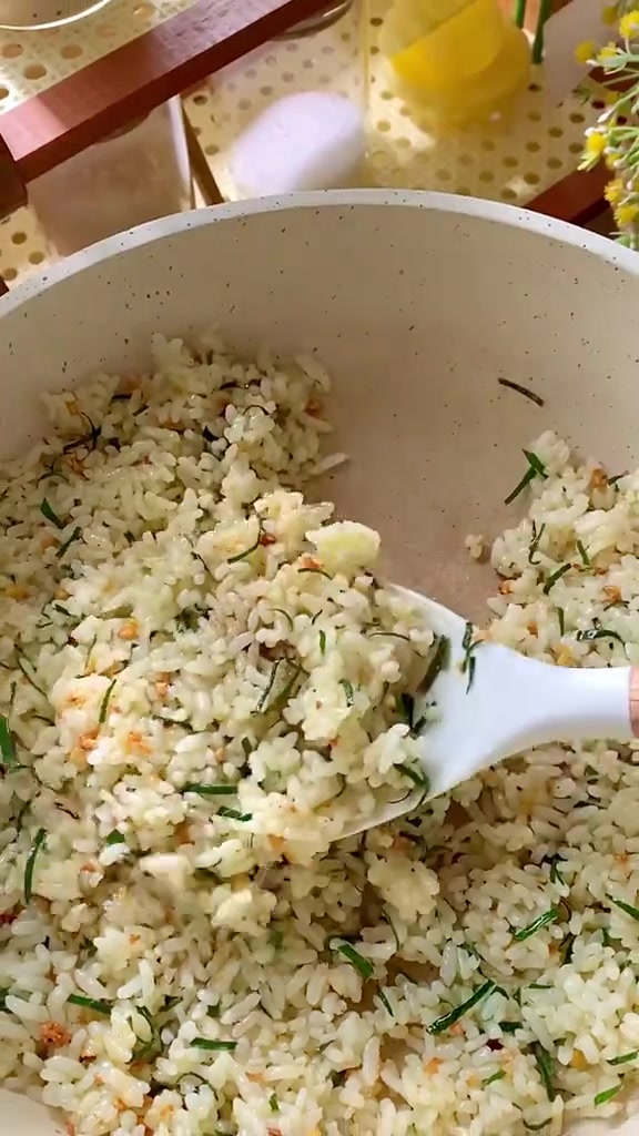 Nasi daun jeruk berbintik irisan daun jeruk di wajan putih, diangkat dengan spatula putih
