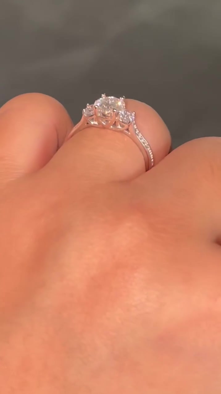 Cincin trilogy tiga batu moissanite berangka rose gold dipakai di jari dengan latar abu-abu