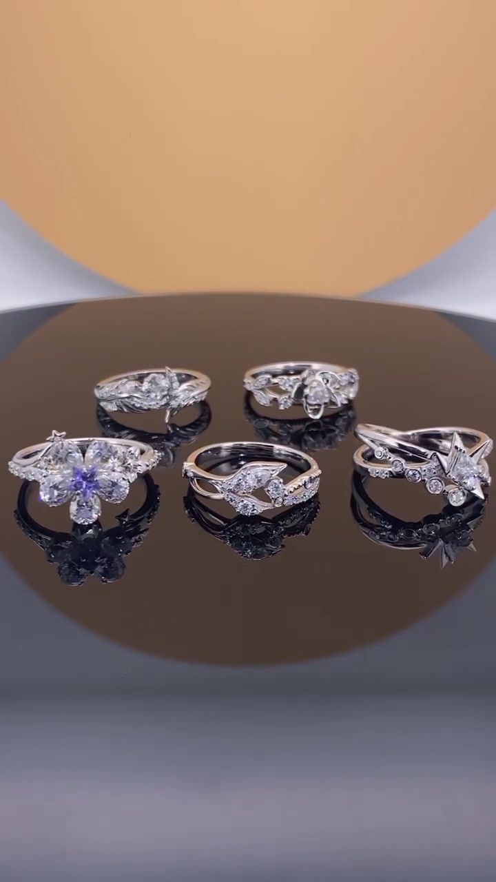 Lima cincin silver berbatu moissanite motif bunga dan bintang disusun di atas permukaan reflektif