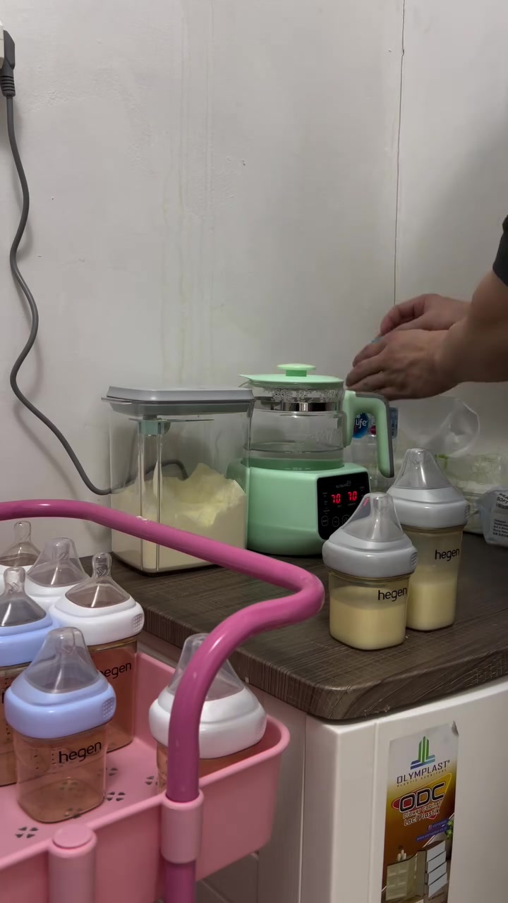 几只 Hegen 奶瓶摆在桌上，旁边是吸奶器和喂养用品