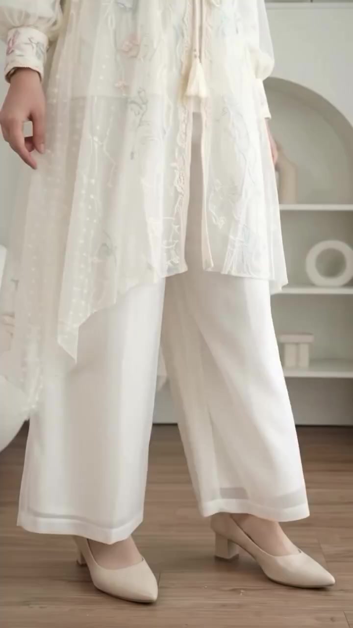 Kebaya outer ivory bertulle dipadukan celana panjang putih dan heels block, difoto dari leher ke bawah di depan cermin