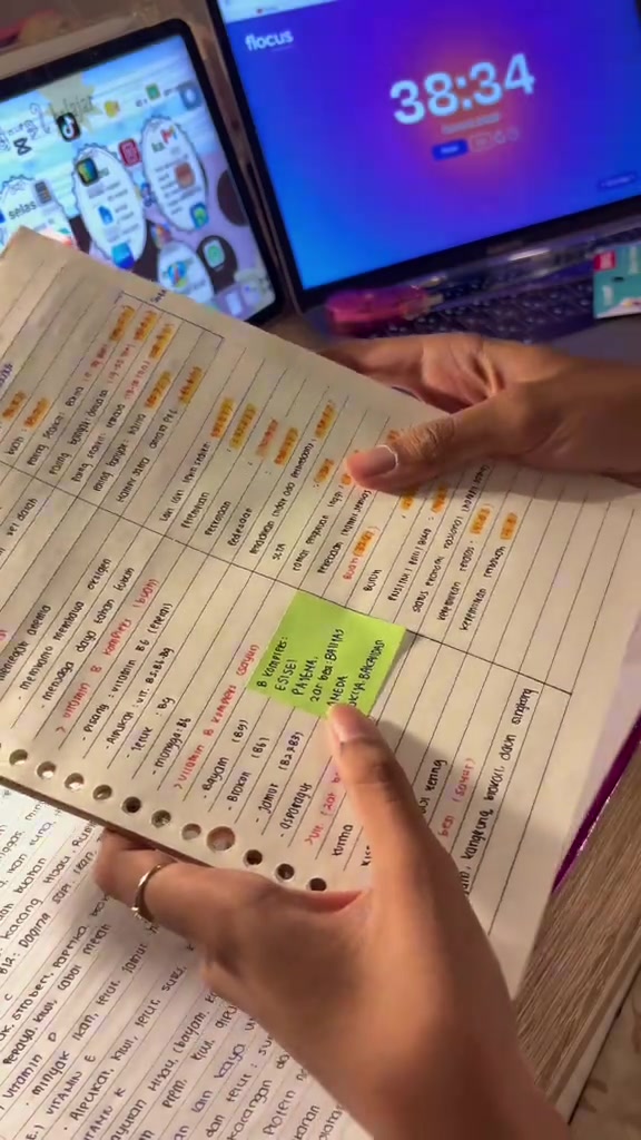 Lembar rangkuman berkolom yang dipegang di atas meja dengan beberapa bagian diberi highlight