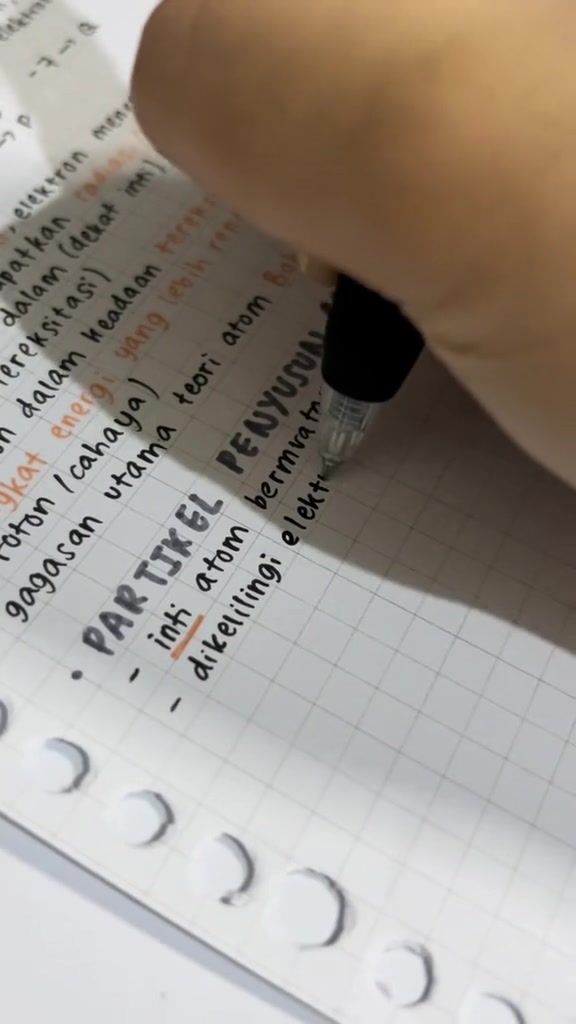 Tangan menulis catatan kimia di buku kotak sambil menandai beberapa kata dengan warna