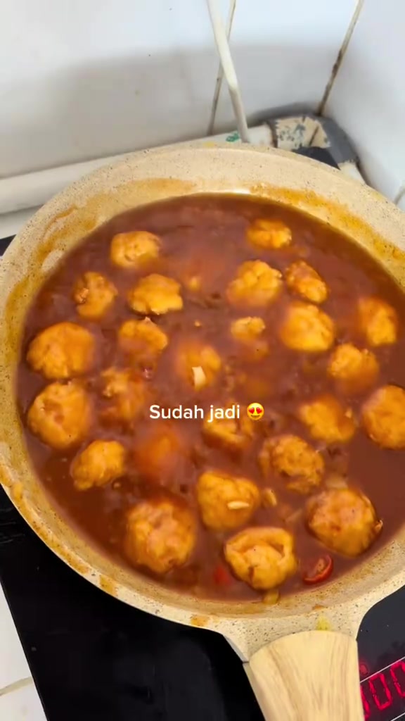 Bola tahu goreng berwarna keemasan di dalam saus barbeque pada wajan