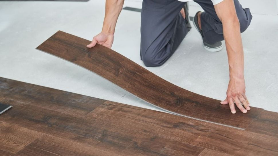 Tangan meratakan bilah vinyl bermotif kayu di atas lantai putih