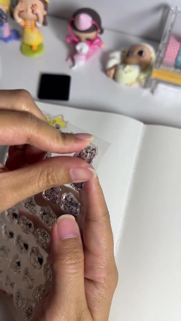 Tangan memegang lembar motif stempel kucing transparan di atas kertas putih