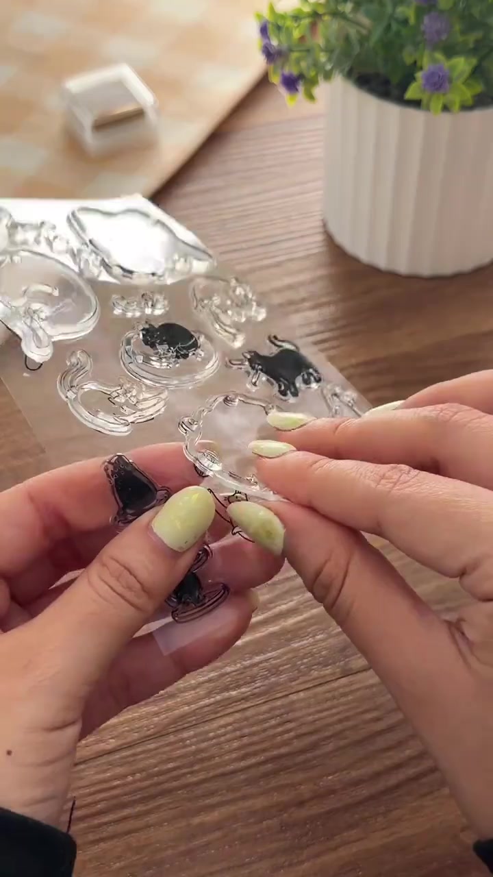 Tangan mengangkat stempel transparan bermotif kucing dari lembarannya