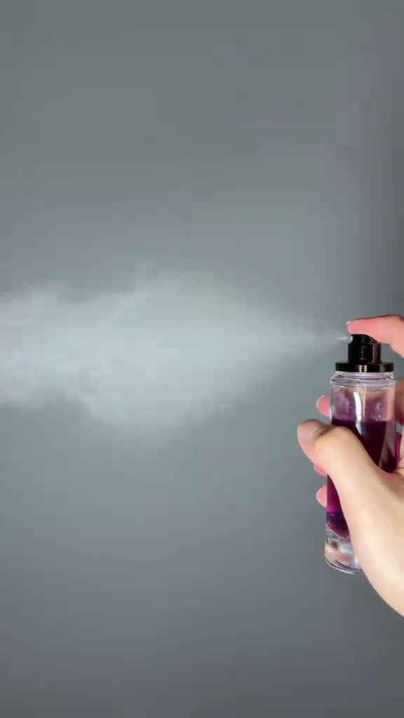 Tangan memegang botol ungu AsterixSty Vansen pada latar abu-abu polos