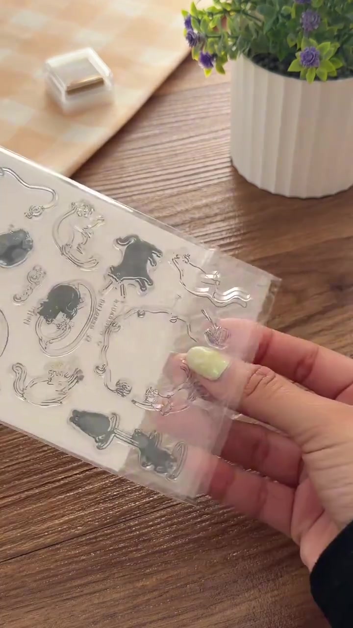 Deretan stempel kucing transparan dipegang di atas meja kayu