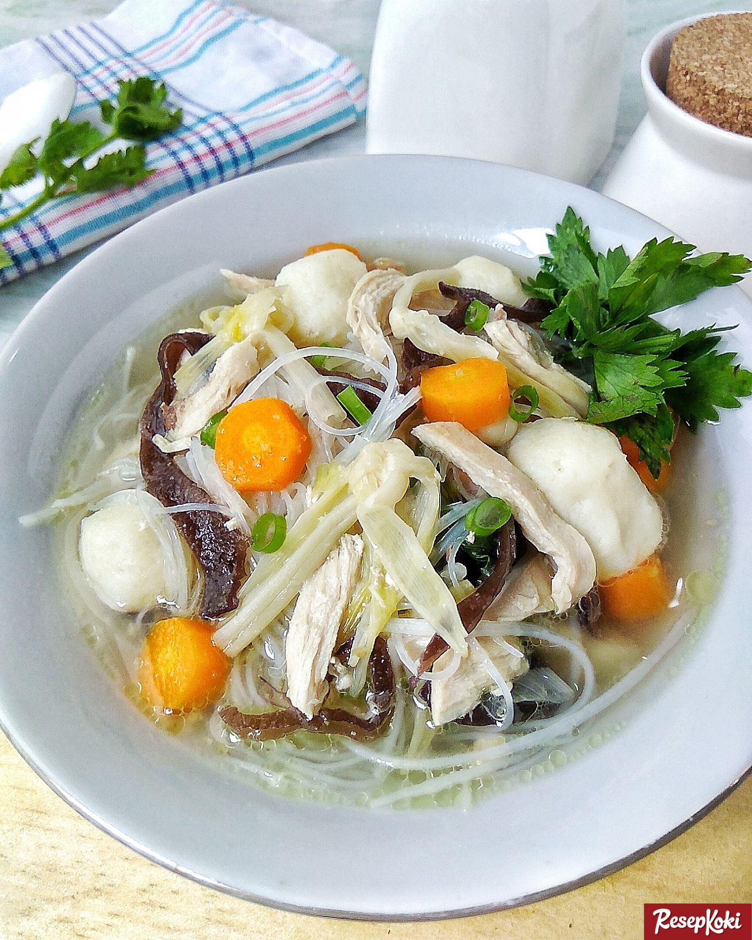 Sup kimlo berkuah bening dengan ayam suwir, wortel, jamur kuping dan soun dalam piring putih