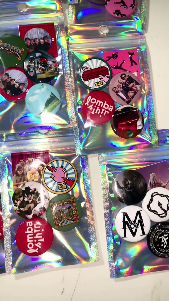 Pin button bulat bertema musik tersusun di atas kemasan reflektif