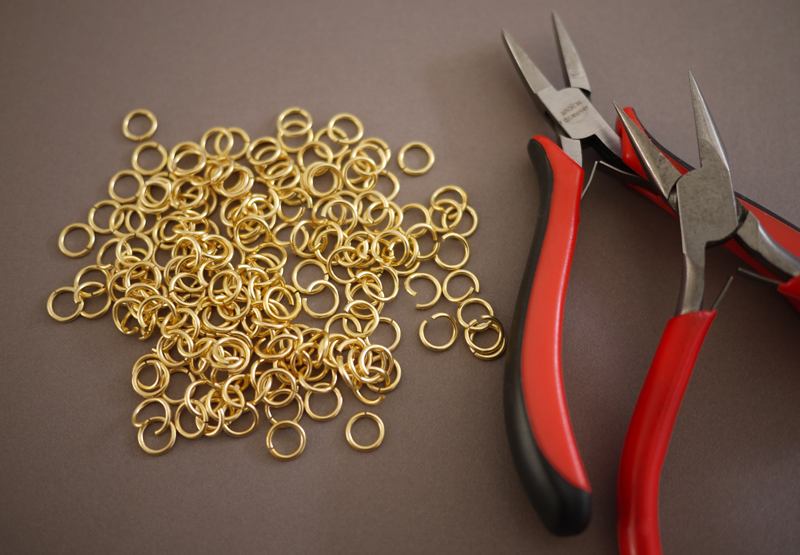 Ring logam kecil dan tang yang digunakan saat merangkai pola chainmail
