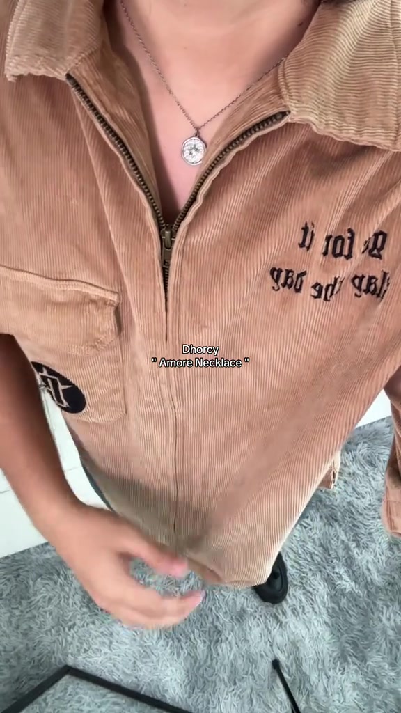 Kalung koin perak dipakai di atas atasan korduroi beige