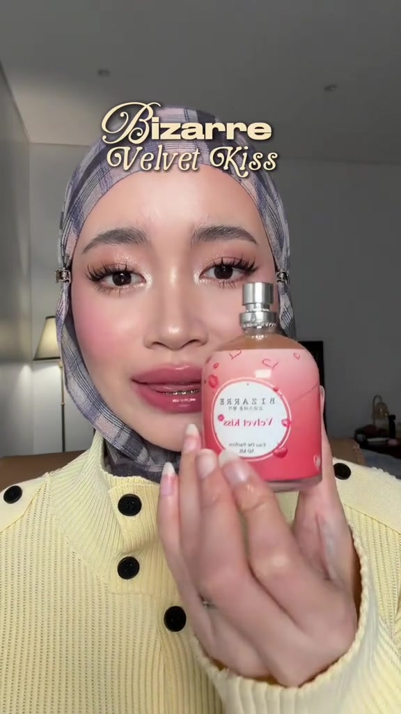 Botol Bizarre Velvet Kiss berwarna merah muda dipegang dekat kamera