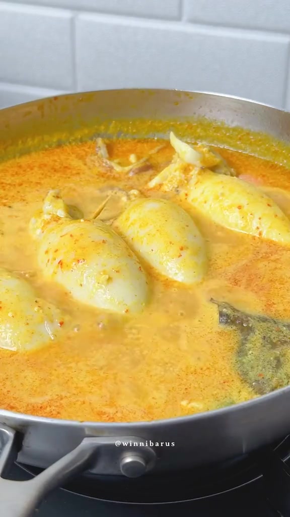 Cumi isi tahu dimasak dalam kuah gulai santan kuning di wajan