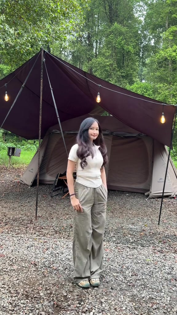 Celana outdoor abu-abu berpotongan longgar dipadukan dengan atasan putih di depan tenda